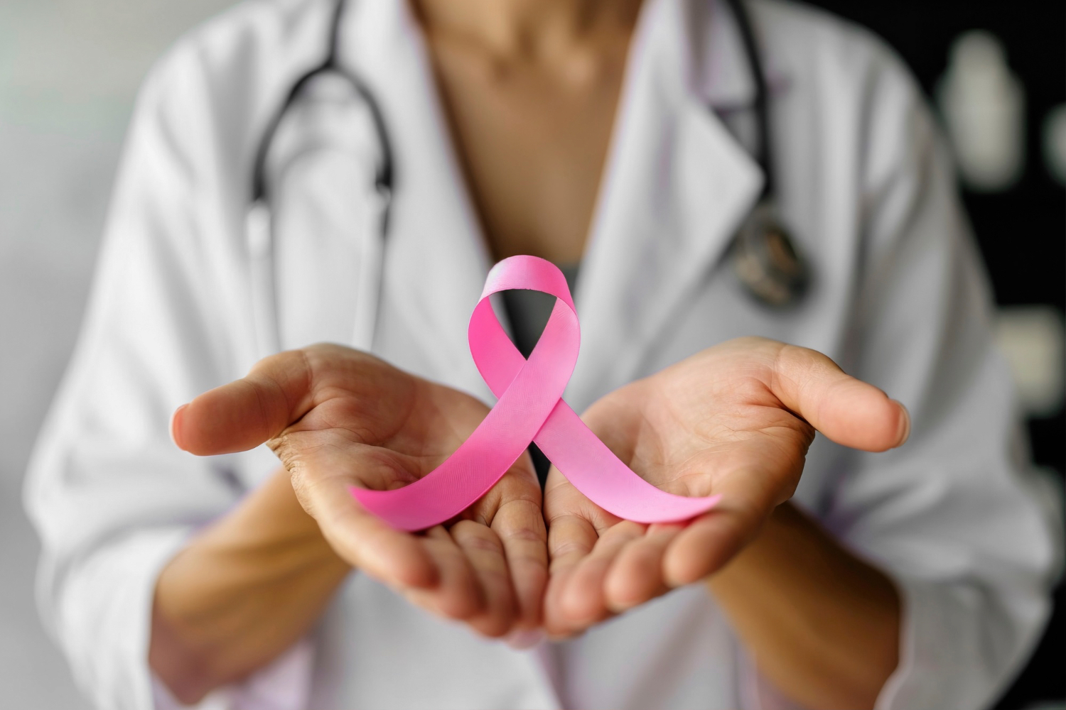 Eine Ärztin hält auf ihren Händen eine rosafarbene Schleife. Die Rosa Schleife steht für Solidarität mit Frauen. 