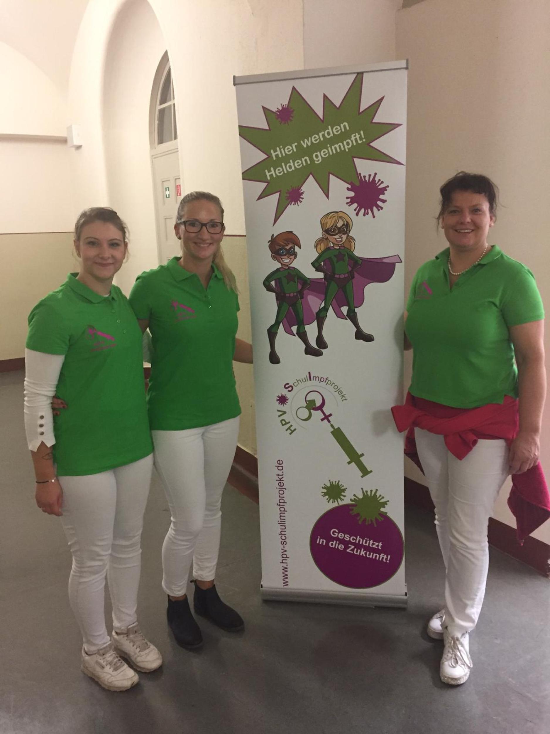 Teammitglieder des Leipziger HPV-Schulprojekts vor einem Aufsteller zur Impfkampagne. 