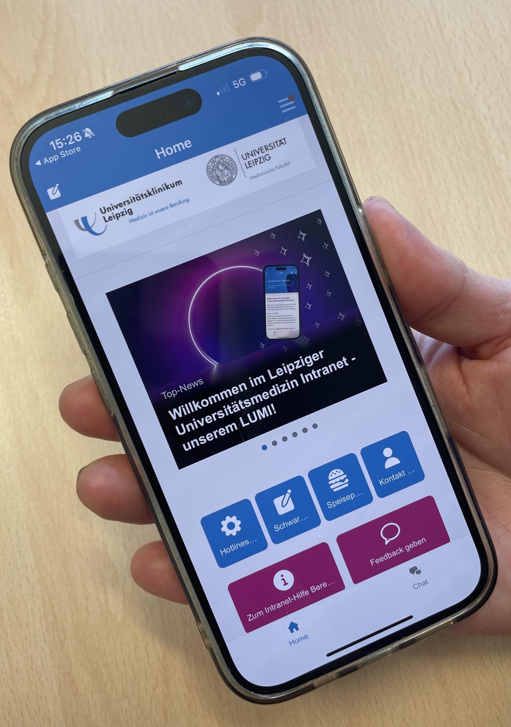 Auf dem Bild ist eine Hand zu sehen, die ein Smartphone hält. Auf dem Smartphone ist der Schriftzug „Willkommen im Intranet der Universitätsmedizin Leipzig – unserem LUMI!“ zu lesen.