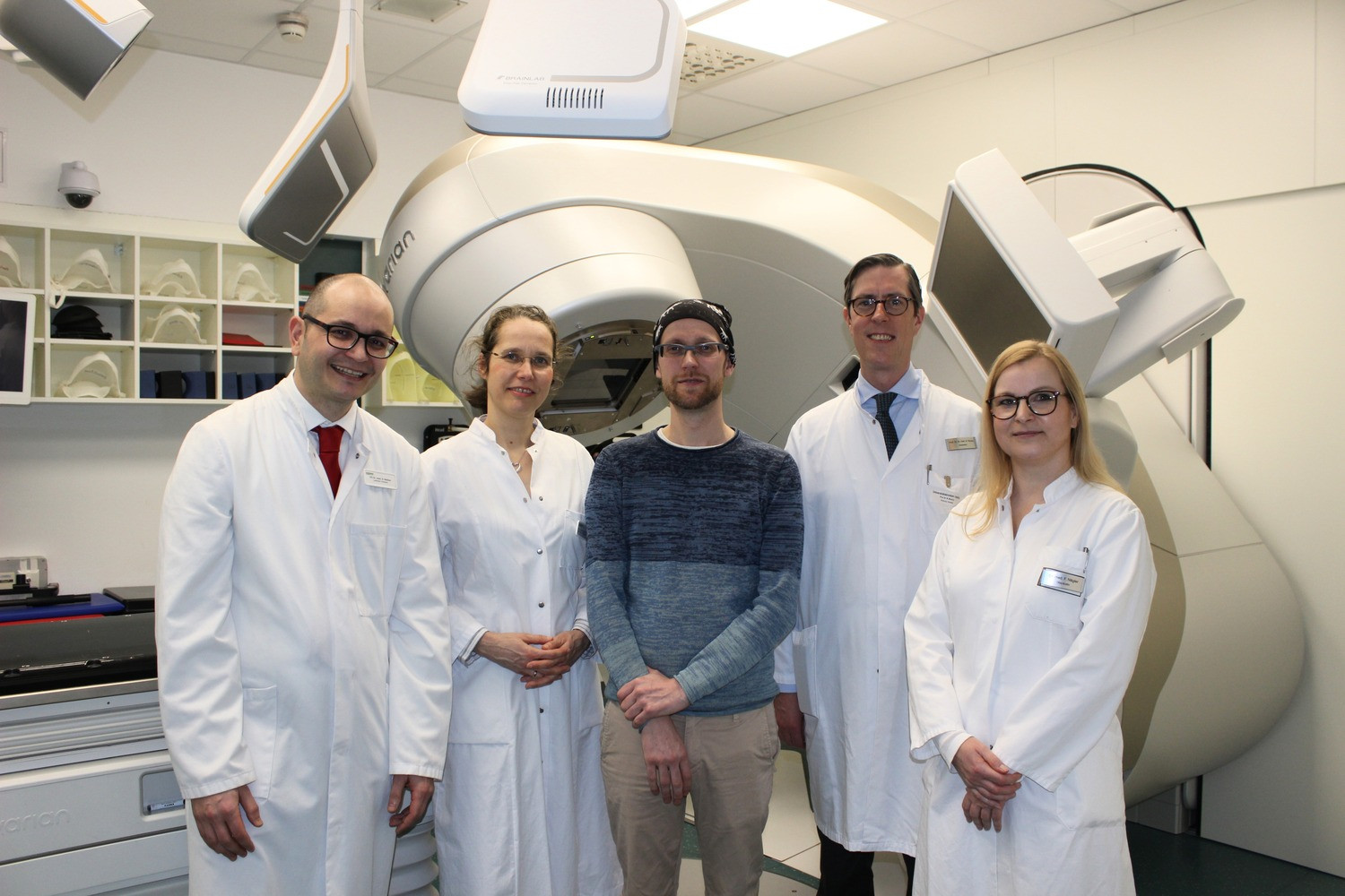 Ärzteteam des Herzzentrums mit dem erfolgreich behandelten Patienten Daniel Hrivnak vor einem speziellen medizinischen Gerät. 