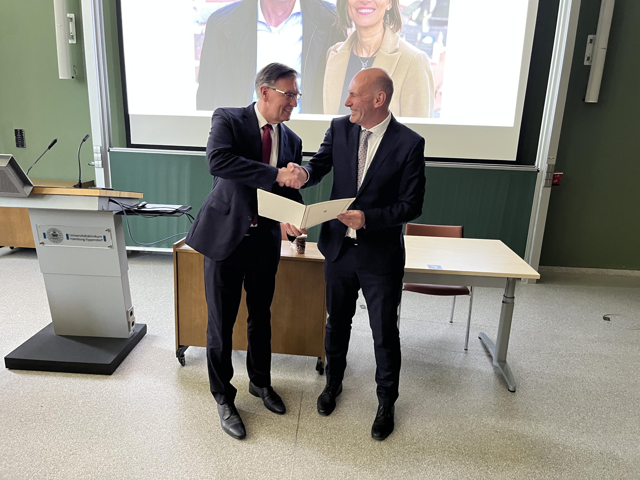 Prof. Carsten Bokemeyer, Vorstand der Wilhelm-Warner-Stiftung und Direktor der Medizinischen Klinik II am Universitätsklinikum Hamburg-Eppendorf (UKE), überreicht Prof. Florian Lordick den Wilhelm-Warner-Preis.